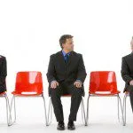 Three Business People Sitting On Red Plastic Seats